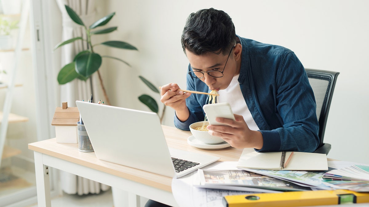 engineer with dessert sitting in front of computer monitor