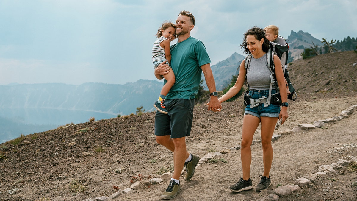 couple holds hands while hiking with children