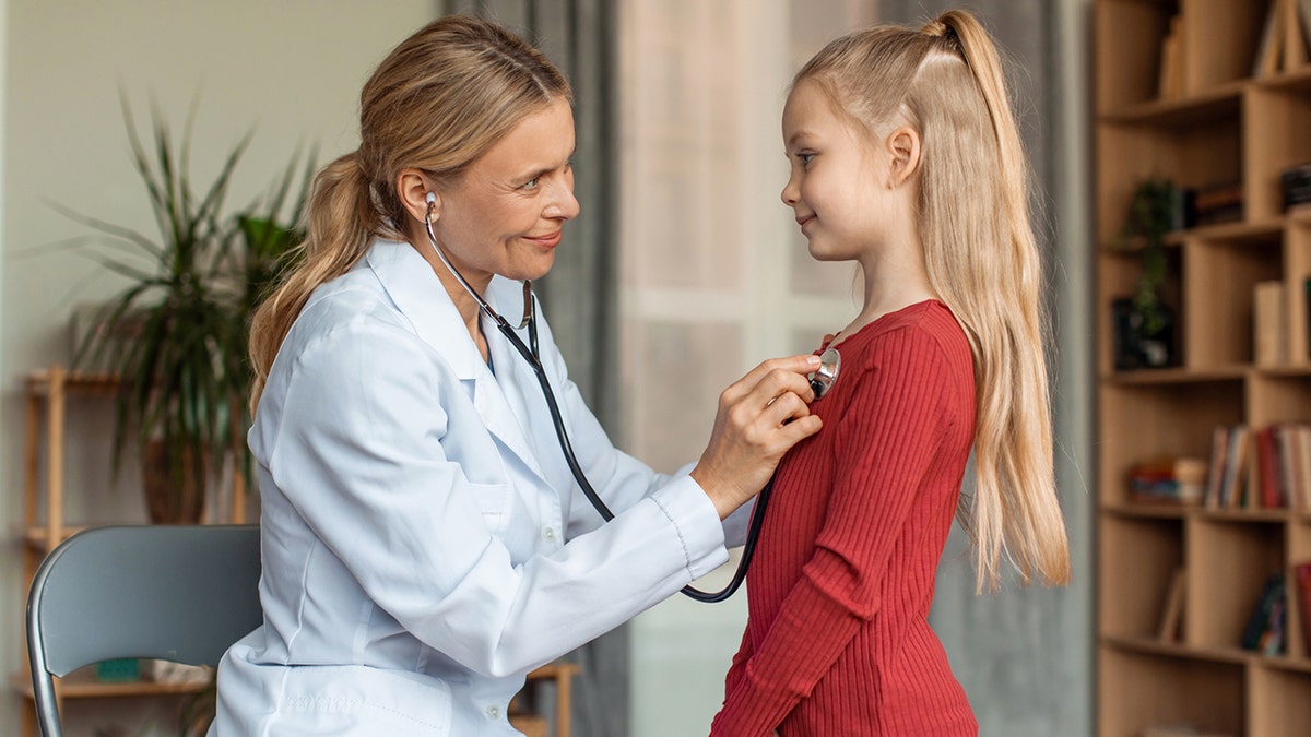 pediatrician listening to girl's heartbeat with stethoscope