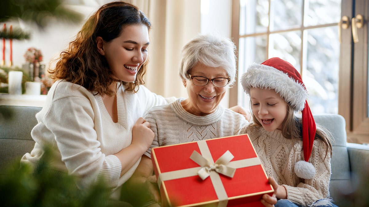 Cheerful kid presenting gifts to mom and granny.