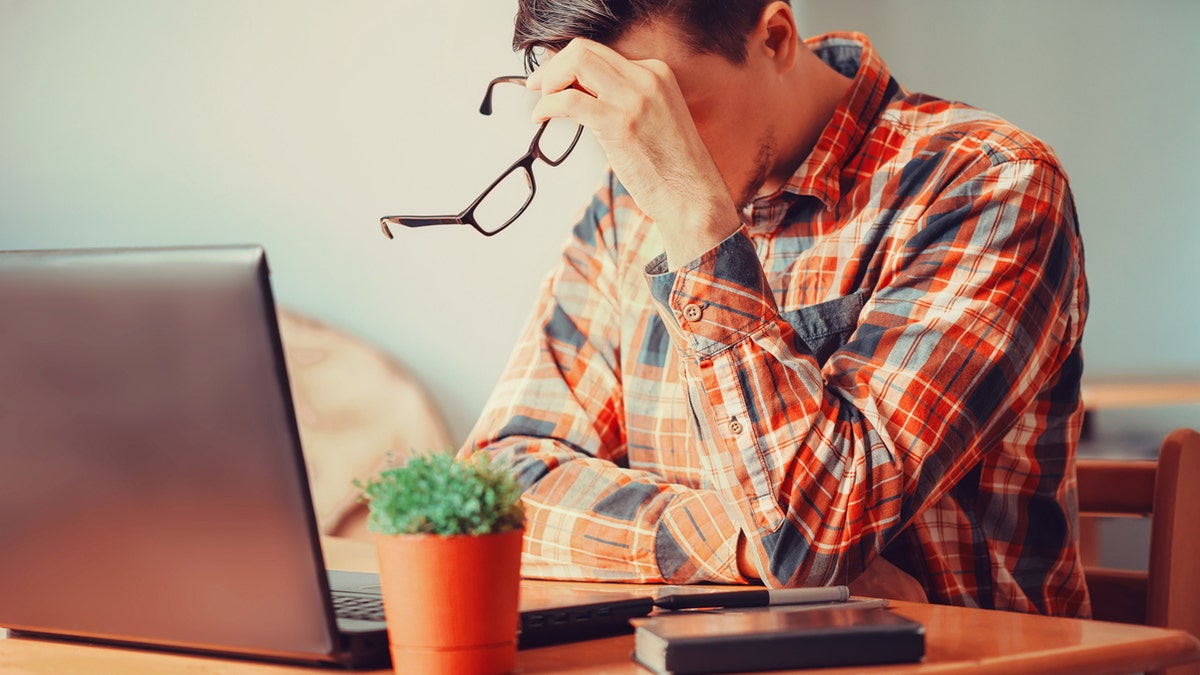 Tired young man sitting over laptop in the office